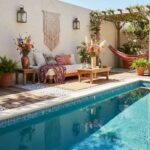 A relaxing backyard space featuring a swimming pool, colorful glass mosaic tiles, and comfortable seating area with vibrant c.