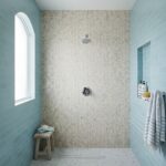 Close-up of a shower wall featuring mother of pearl shell tile with a herringbone pattern, complemented by blue subway tiles.