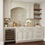 Elegant kitchen with mother of pearl shell tile backsplash, white cabinetry, and open wooden shelves.