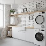 Laundry room with white cabinets and black and white patterned tile backsplash.