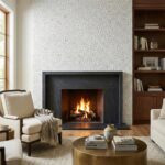 Cozy living room featuring a white crackle tile fireplace with a black frame, surrounded by comfortable beige armchairs, a wo.