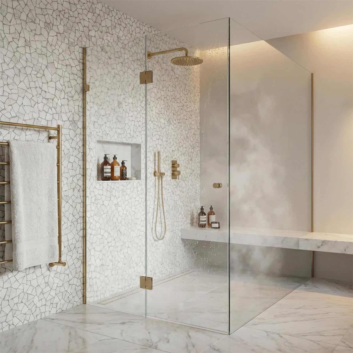 Elegant white marble tile with subtle veining, complemented by gold fixtures and a clear glass shower enclosure.