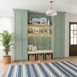Green built-in wall with peel and stick tile backsplash, shelves, and seating area in a modern home interior.