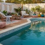 A relaxing outdoor space featuring a swimming pool with glass mosaic tiles, surrounded by comfortable seating, potted plants,.