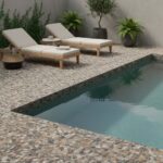 A close-up of a pebble tile pool deck featuring natural stone with multicolor pebbles and textured surface for slip resistanc.