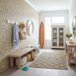 Bright entryway with peel and stick tile wall, bench, and surfboard, creating a welcoming coastal-inspired space.