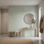 Green and white chevron patterned tile wall with a round mirror, wooden bench, and decorative vase in a modern entryway.