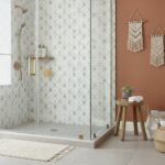 Light-colored geometric patterned shower tiles with textured surface.