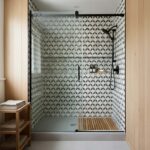 Geometric patterned ceramic tile in black, white, and beige, with a textured matte finish, used on shower walls.