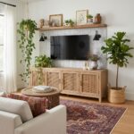 Aesthetic living room wall decor featuring a wooden shelf with framed art, potted plants, and decorative vases, creating a co.