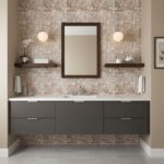 A modern bathroom vanity with glass mosaic tile backsplash, mirror, and wall-mounted lighting fixtures. Stylish and functiona.