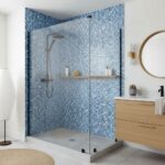 Blue glass tile backsplash in a contemporary bathroom with a glass shower enclosure and wooden vanity.