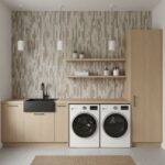Bright laundry room with beige mosaic tile wall, black sink, and wooden cabinetry, featuring a washing machine and dryer.