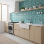 A modern kitchen featuring a vibrant glass tile backsplash with shades of blue and green, complemented by light wood cabinets.