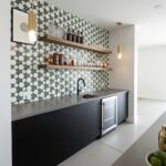 Geometric patterned tile in shades of gray and white with a matte finish, installed behind a sleek black countertop and open.