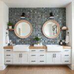Double sink bathroom with glass mosaic tile backsplash and round mirrors.