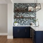 Beautiful glass mosaic tile backsplash with blue cabinetry and open shelving.