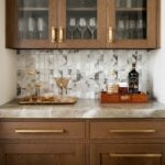 Glass tile backsplash with marble accents and wooden cabinetry.