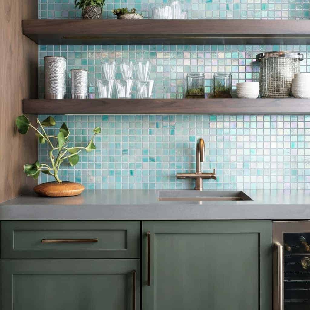 Bright glass mosaic tile backsplash behind kitchen sink and shelves.