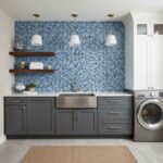 Bright blue glass mosaic tile wall behind sink and open shelves.