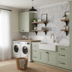 Bright laundry room featuring sage green cabinets, white farmhouse sink, and textured gray and white tile backsplash.