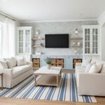 Modern living room with peel and stick wall tile behind TV, featuring white sofas and striped rug.
