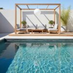 Outdoor lounge area with wooden pergola, cushions, and glass mosaic tile pool edge.