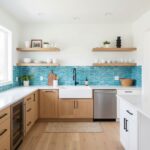 Bright kitchen with vibrant blue glass tile backsplash, white and wood cabinetry, and minimalist decor.