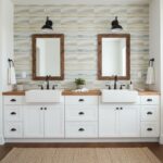 Bathroom vanity with double sinks, wooden framed mirrors, and glass mosaic backsplash tiles.