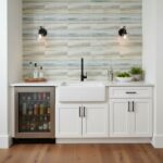 Glass tile backsplash, modern kitchen, white cabinetry, black fixtures, minimalist design.