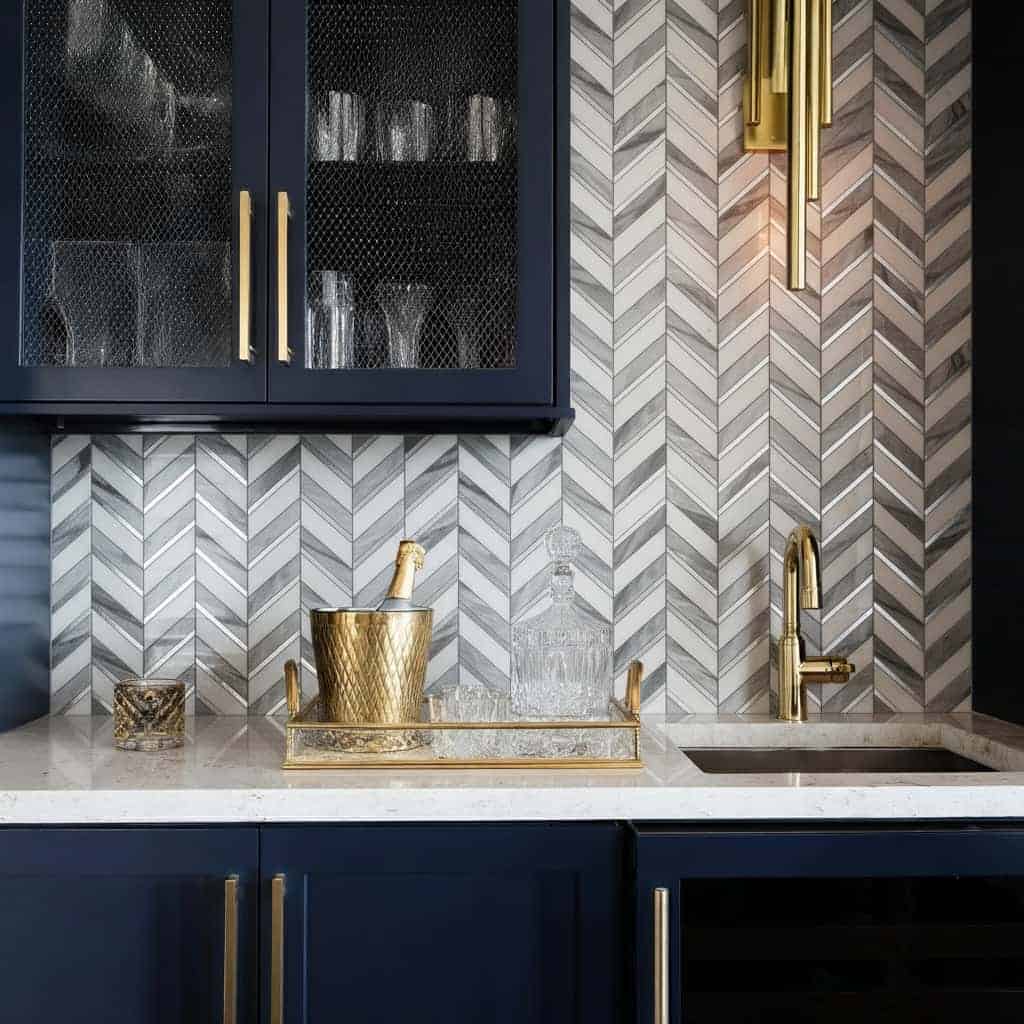Modern kitchen backsplash with peel and stick tile in a herringbone pattern, featuring gold accents and navy cabinetry.