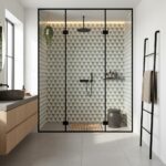 Geometric patterned tiles in neutral tones with matte finish, black fixtures, and wooden mat in a contemporary bathroom showe.