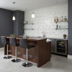 Seashell tile backsplash in a contemporary kitchen with a bar counter, black chairs, and minimalist decor.