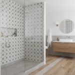 Geometric patterned tiles in neutral tones, textured surface, with a sleek glass shower door.