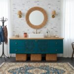 Modern bathroom vanity with peel and stick tile backsplash, round mirror, and stylish decor.