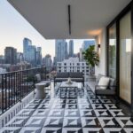 Balcony with black and white geometric patterned tiles, modern outdoor furniture, and city skyline view.