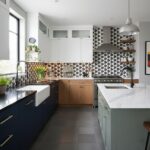 A modern kitchen featuring black and white patterned tiles on the backsplash, complemented by white and wooden cabinetry, and.
