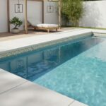 Pool with glass mosaic tile border and surrounding outdoor lounge area.