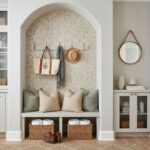 A cozy entryway with a built-in bench, pillows, and a decorative shell tile wall featuring mother of pearl and oyster shell a.