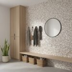 A stylish entryway with a mosaic shell tile wall, round mirror, and storage baskets, creating a natural and elegant home acce.
