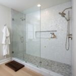 Shower wall featuring elegant mother of pearl shell tiles with a built-in niche and modern fixtures. Perfect for luxurious ba.