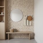 A stylish entryway with a shell tile accent wall, round mirror, and hooks for hats and bags, creating a coastal-inspired home.