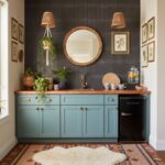 Bright blue kitchen cabinets with wooden countertop, surrounded by framed botanical art, hanging wicker lamps, and a round mi.