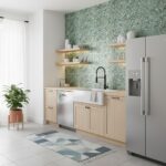 A modern kitchen featuring peel and stick tile backsplash with green mosaic tiles, light wood cabinets, and stainless steel a.