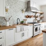 Modern kitchen with white cabinets and a glass tile backsplash behind the stove and sink.