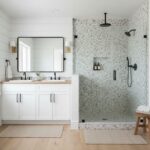 Glass tile bathroom shower with mosaic backsplash, featuring a modern walk-in design, black fixtures, and a spacious, bright.