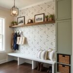 Decorative shell tile wall with mother of pearl accents in a cozy entryway. Features a wooden shelf, framed photos, and a bui.