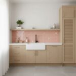 A contemporary kitchen featuring a pink glass tile backsplash, white sink, and light wood cabinetry.