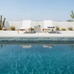 Poolside outdoor space with modern lounge chairs and desert plants, featuring a clear blue swimming pool.