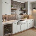 Modern kitchen with glass tile backsplash, white cabinets, and a stainless steel sink.